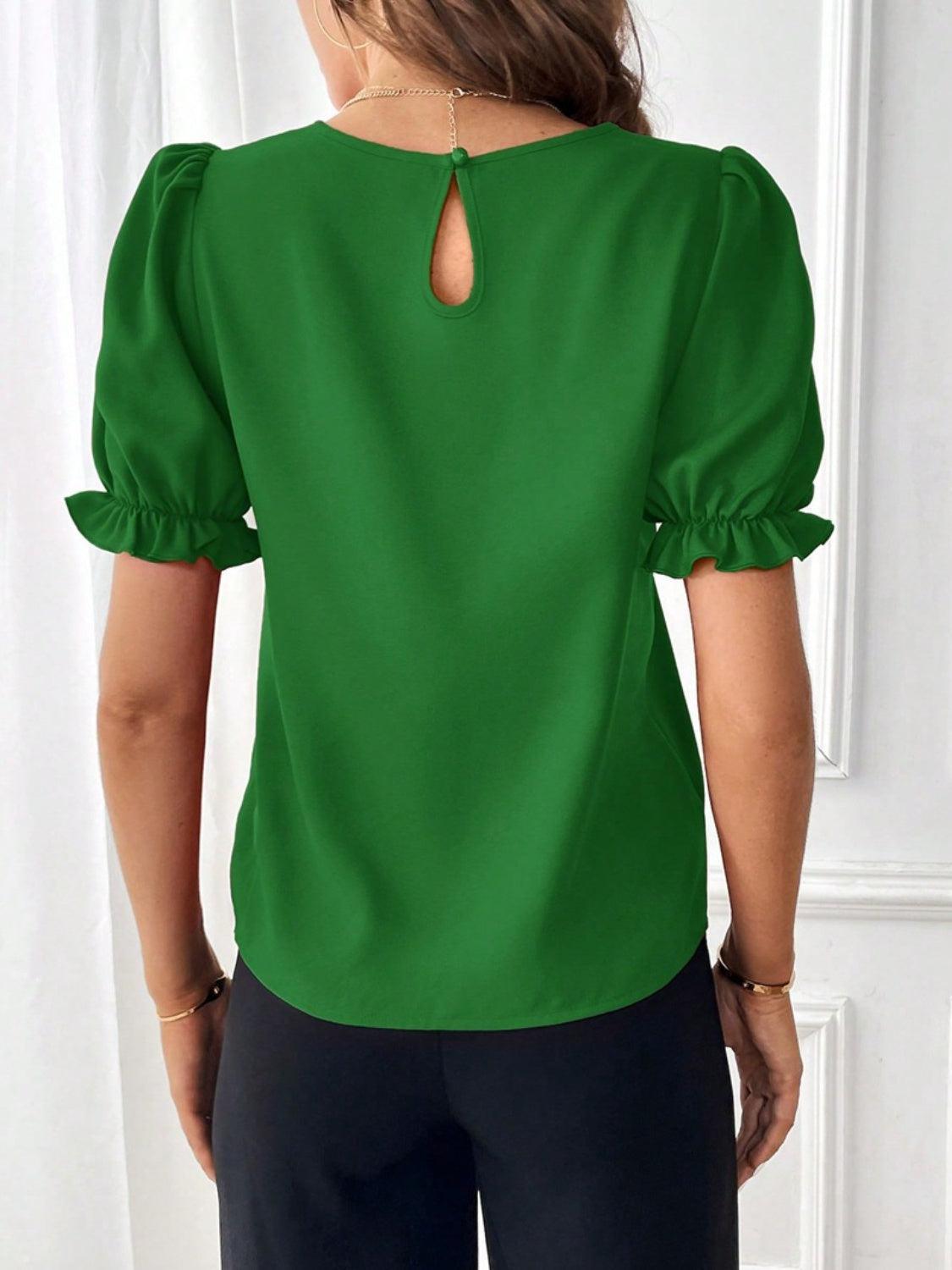 a woman wearing a green blouse and black pants