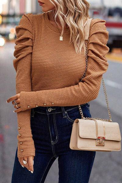 a woman wearing a brown sweater and jeans