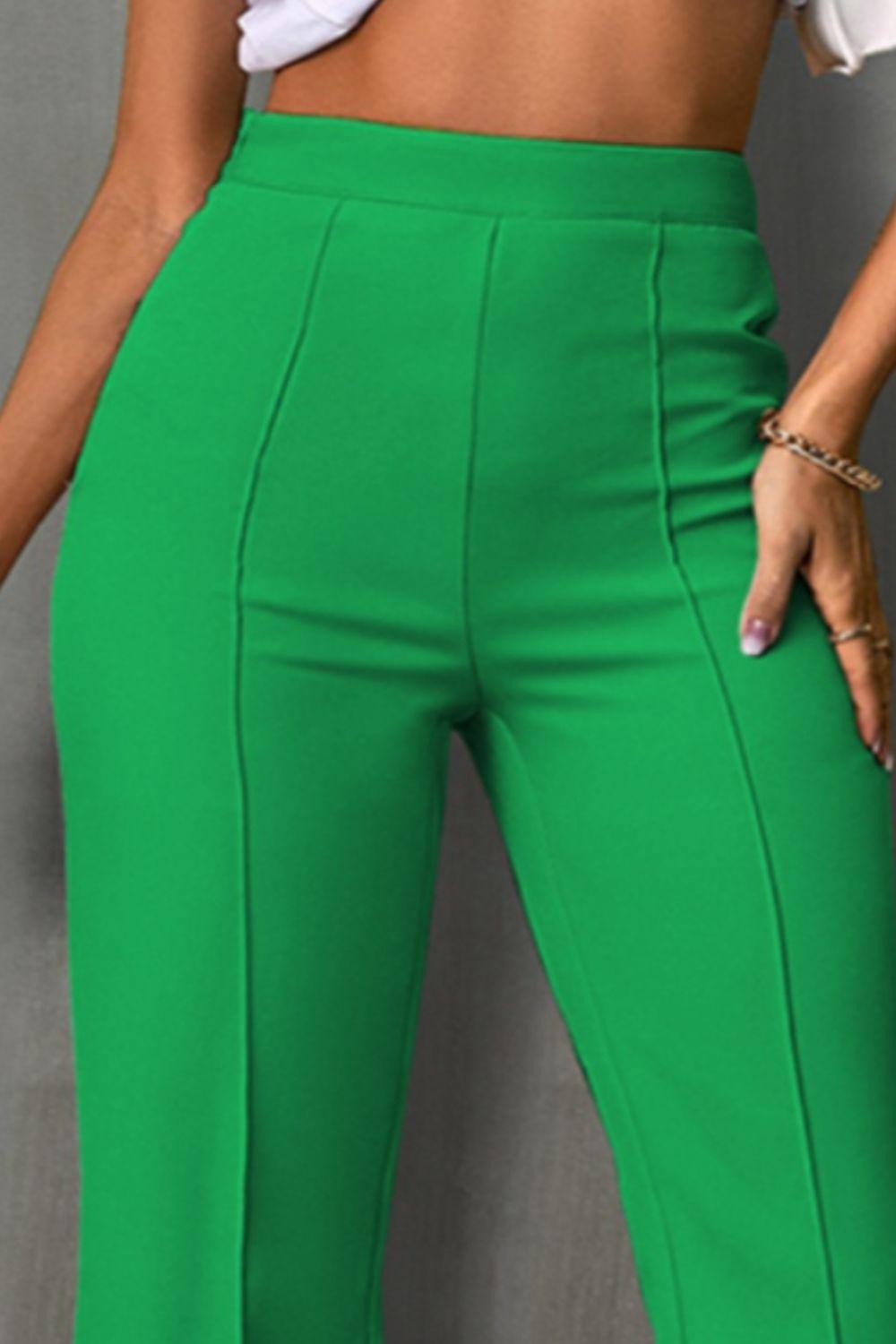 a woman in a white top and green pants