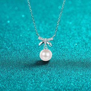 a necklace with a pearl and a bow on it