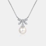 a necklace with a bow and a pearl