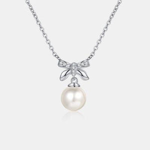 a necklace with a bow and a pearl