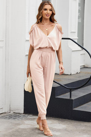 a woman wearing a pink jumpsuit and heels