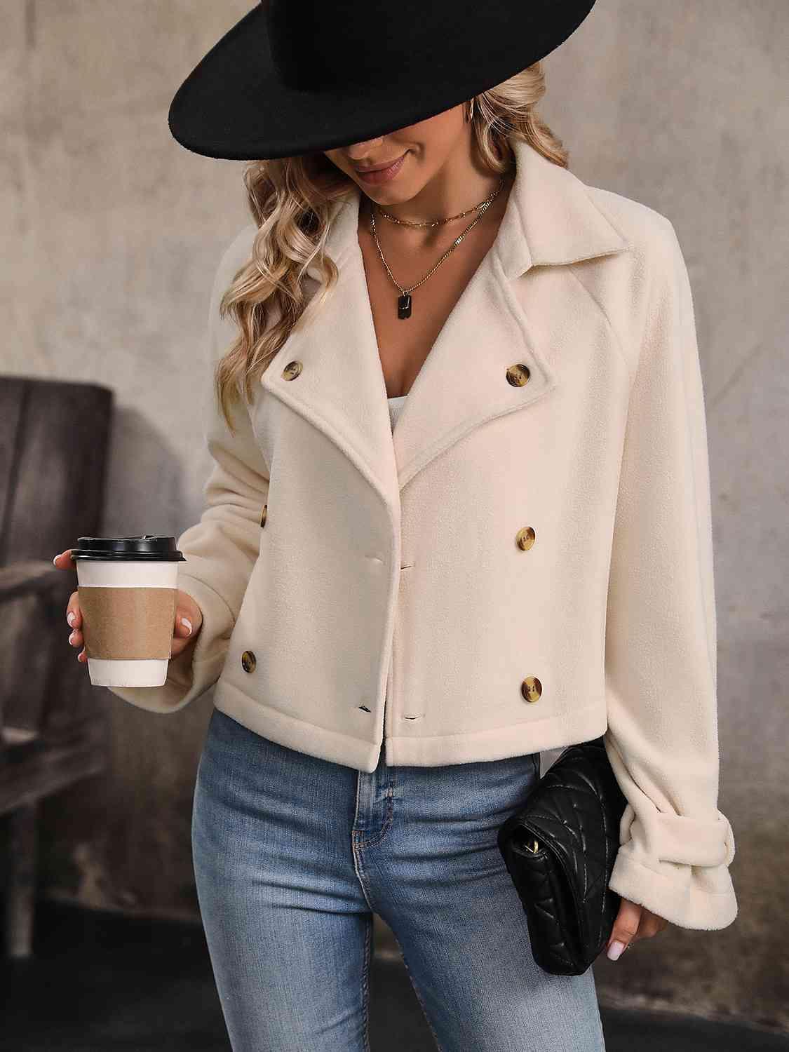 a woman in a white coat and black hat holding a cup of coffee