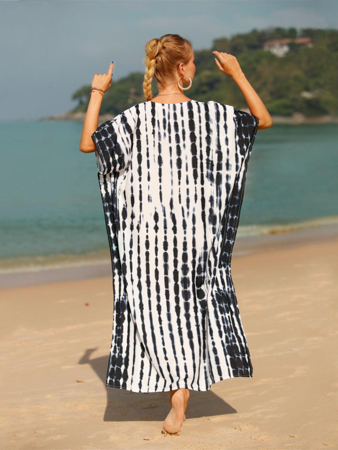 a woman in a black and white towel walking on the beach