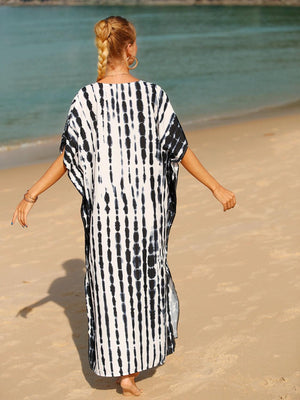 a woman in a black and white dress walking on the beach