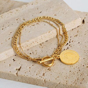 a close up of a gold bracelet with a coin on it