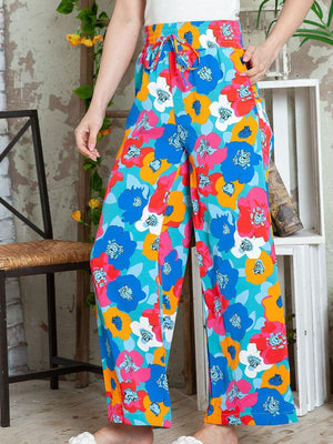 a woman standing in front of a chair wearing colorful pants