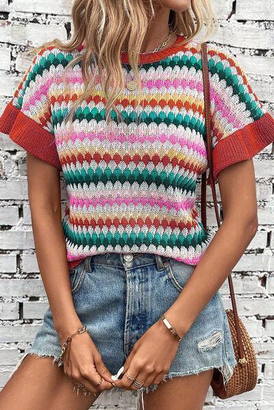 a woman wearing a multicolored sweater and denim shorts