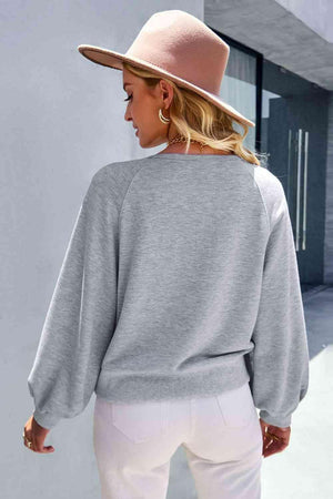 a woman wearing a grey sweater and white pants