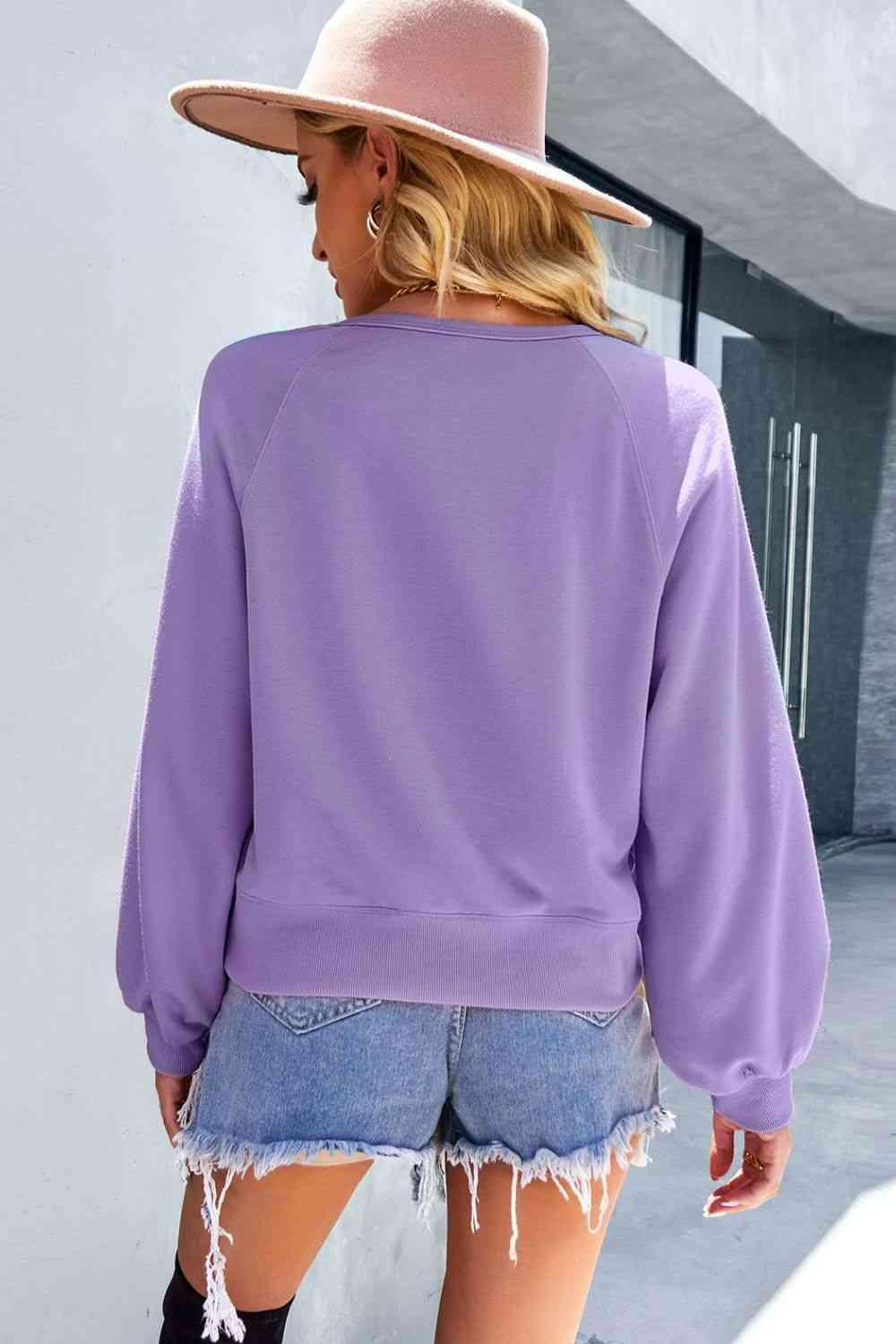 a woman wearing a purple sweatshirt and denim shorts