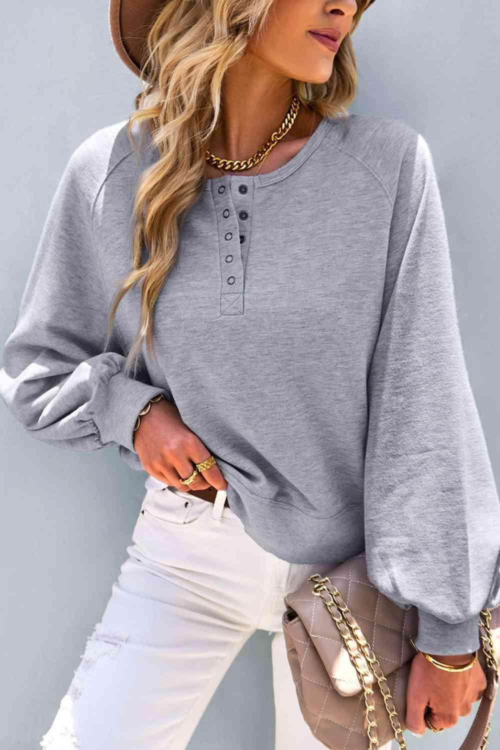 a woman wearing a grey sweater and white jeans