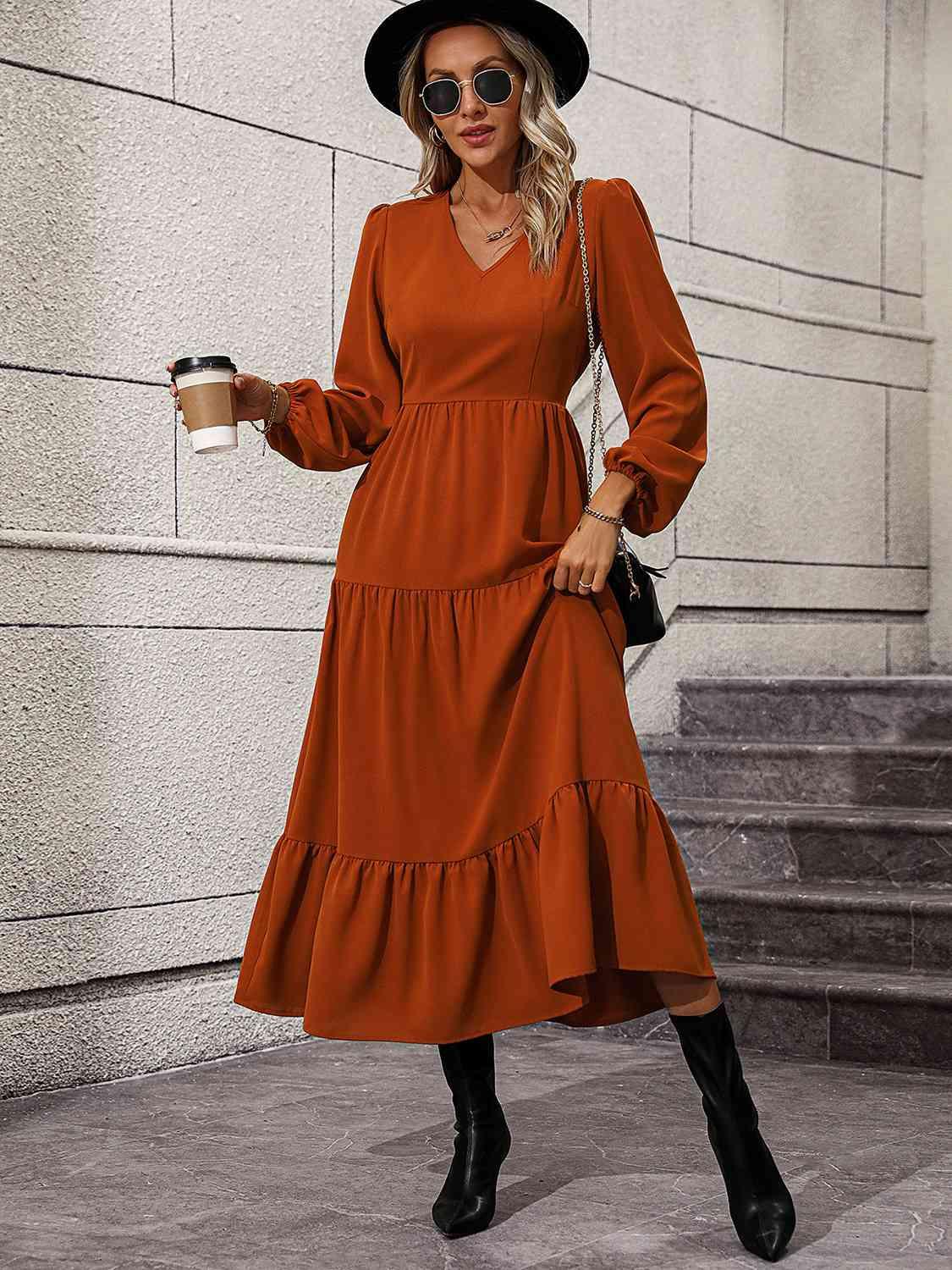 a woman in an orange dress and hat holding a cup of coffee