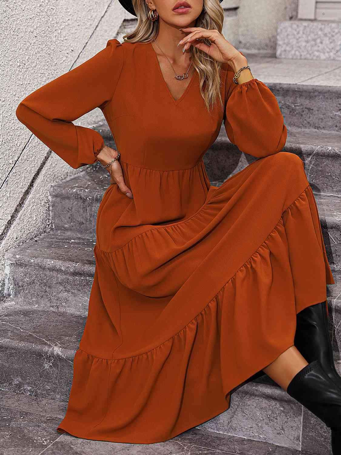 a woman sitting on steps wearing a brown dress