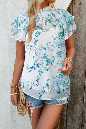 a woman wearing a white top with blue flowers on it