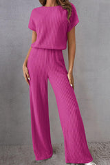 a woman in a pink top and wide legged pants