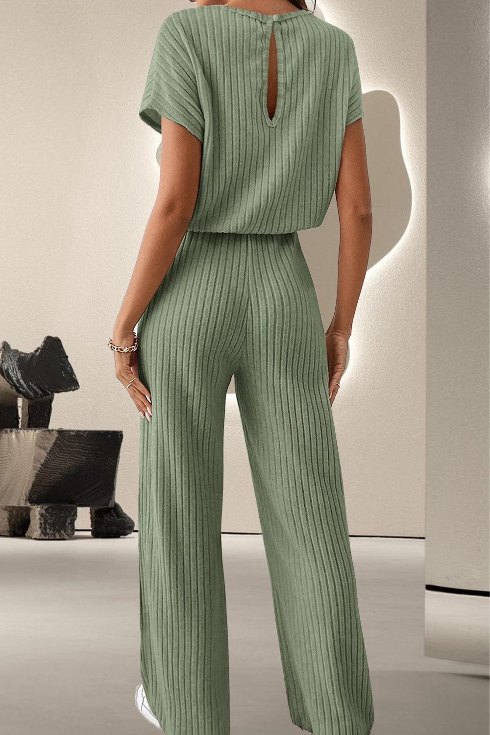 a woman wearing a green jumpsuit and white sneakers