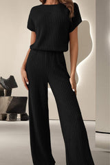 a woman in a black top and wide legged pants