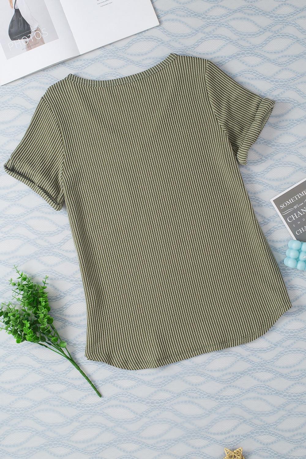 a t - shirt laying on top of a bed next to a flower
