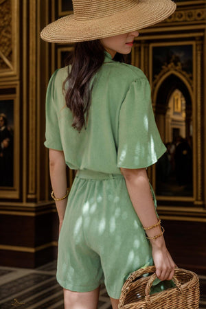 a woman in a green romper and a straw hat