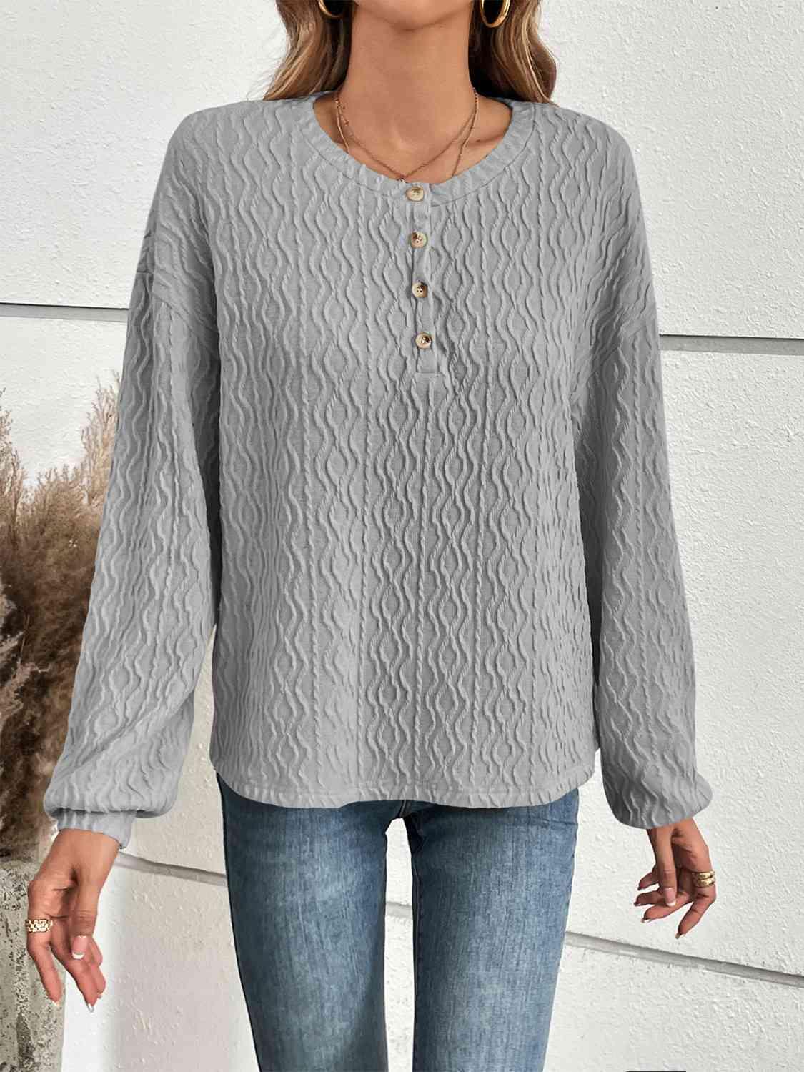 a woman wearing a gray sweater and jeans