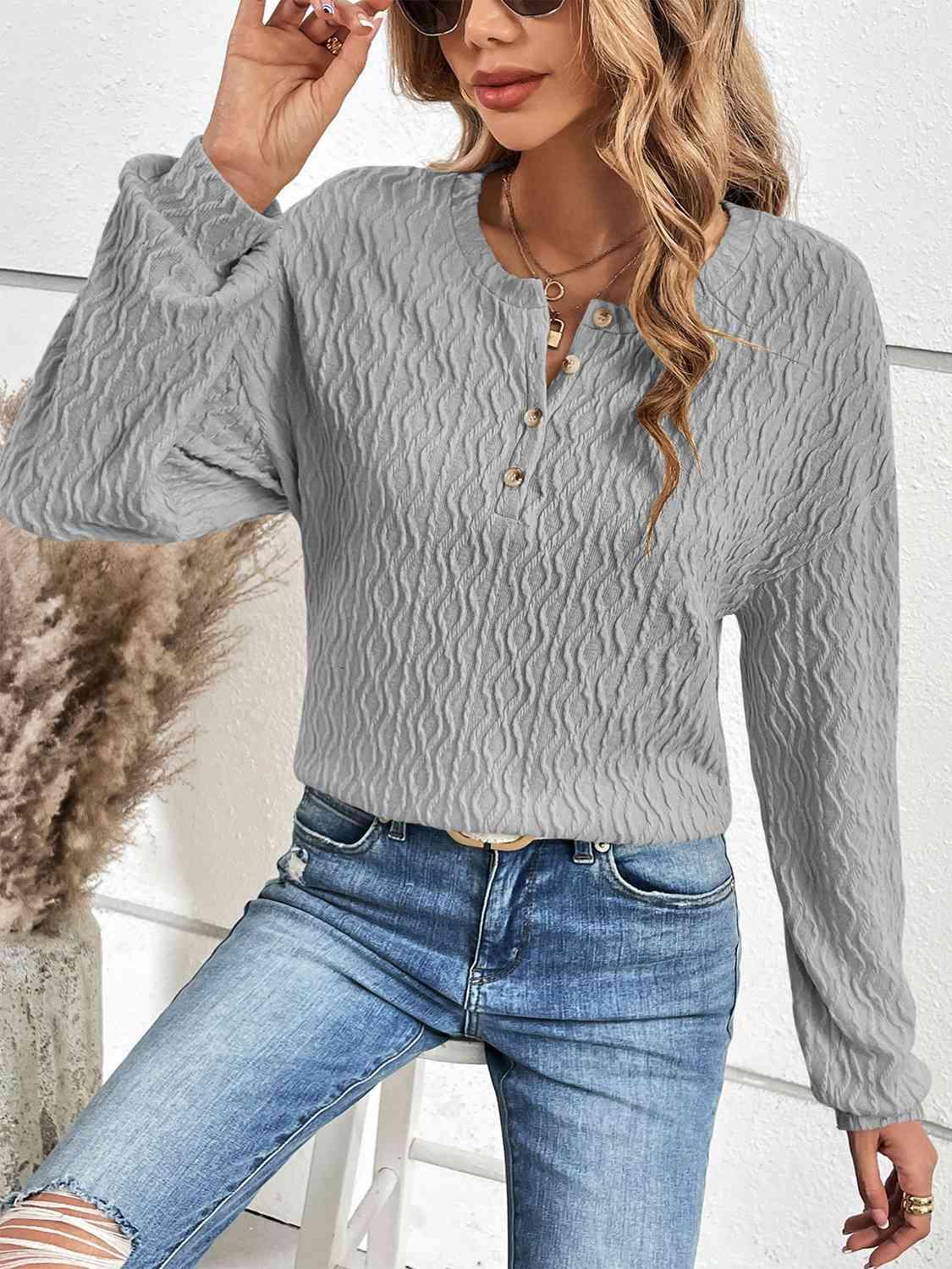 a woman wearing a gray sweater and ripped jeans