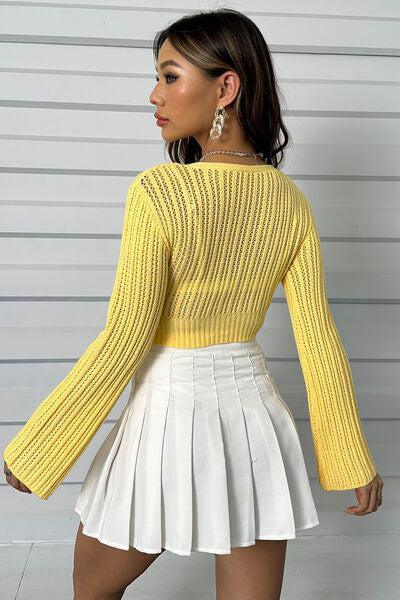 a woman wearing a yellow sweater and white pleated skirt