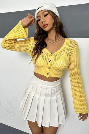 a woman wearing a yellow sweater and a white skirt