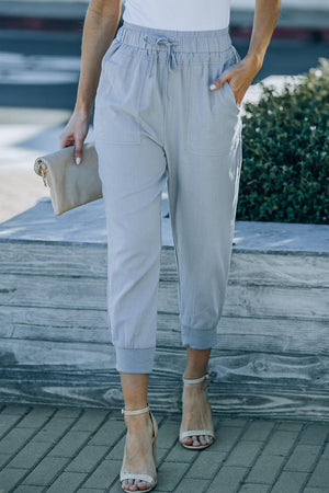 a woman in a white top and grey pants