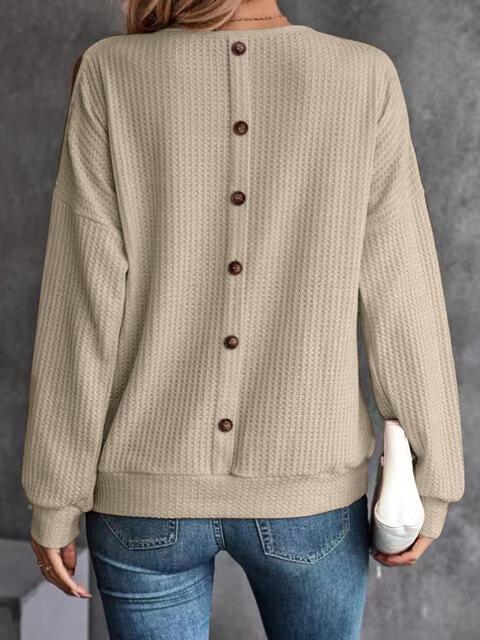 a woman wearing a beige sweater and jeans