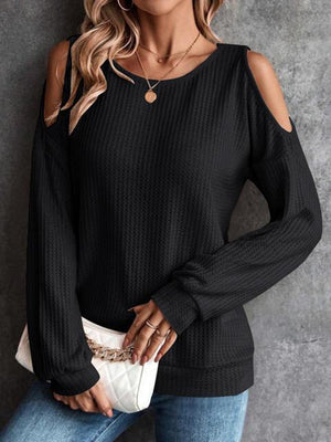 a woman wearing a black cold shoulder sweater