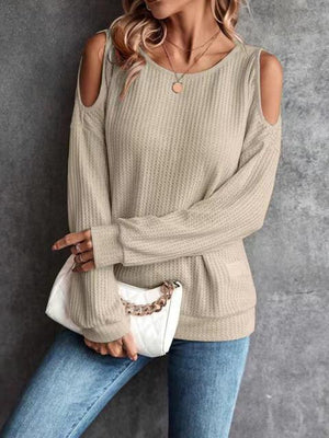 a woman wearing a tan sweater and jeans