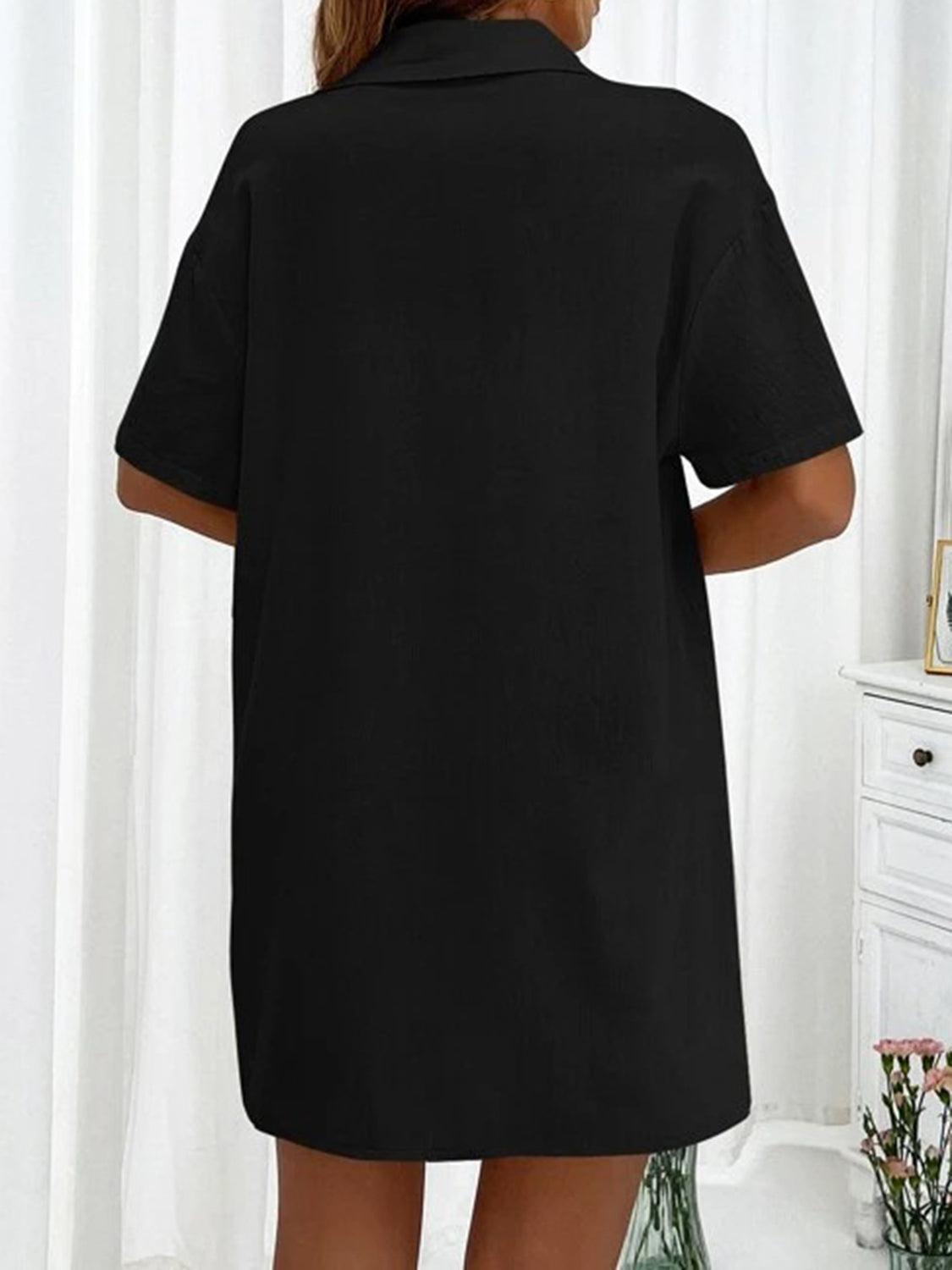 a woman wearing a black shirt dress in front of a mirror