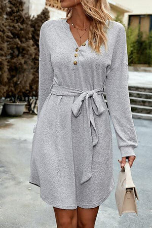 a woman wearing a gray dress with a belt