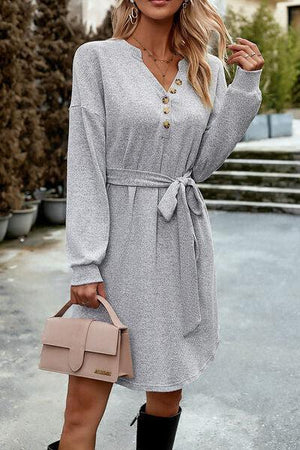 a woman wearing a gray dress and black boots