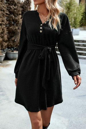 a woman in a black dress is walking down the street