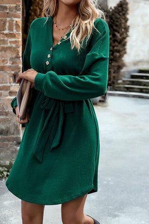 a woman wearing a green dress and black boots