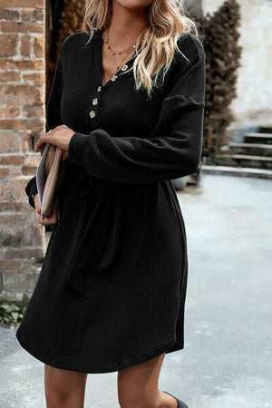 a woman in a black dress is walking down the street