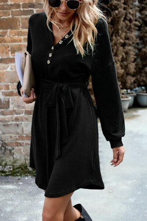 a woman in a black dress is walking down the street