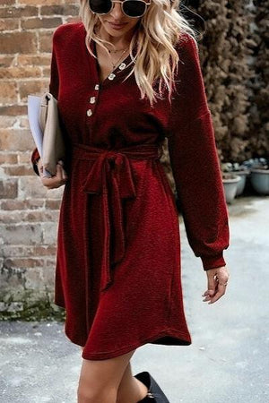 a woman in a red dress and hat walking down the street