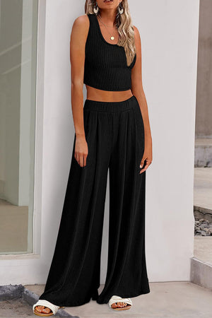 a woman wearing a black crop top and wide legged pants