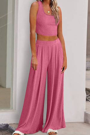 a woman wearing a pink top and wide legged pants