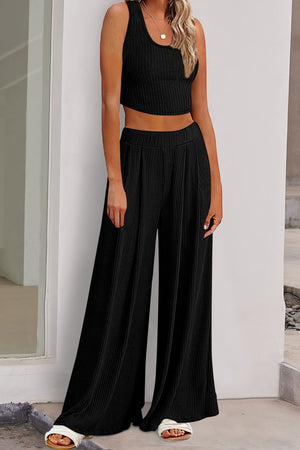 a woman wearing a black crop top and wide legged pants