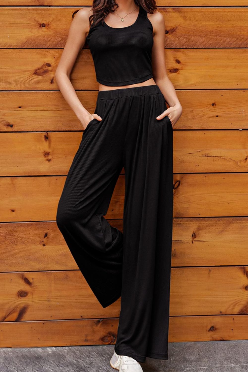 a woman wearing a black crop top and wide legged pants