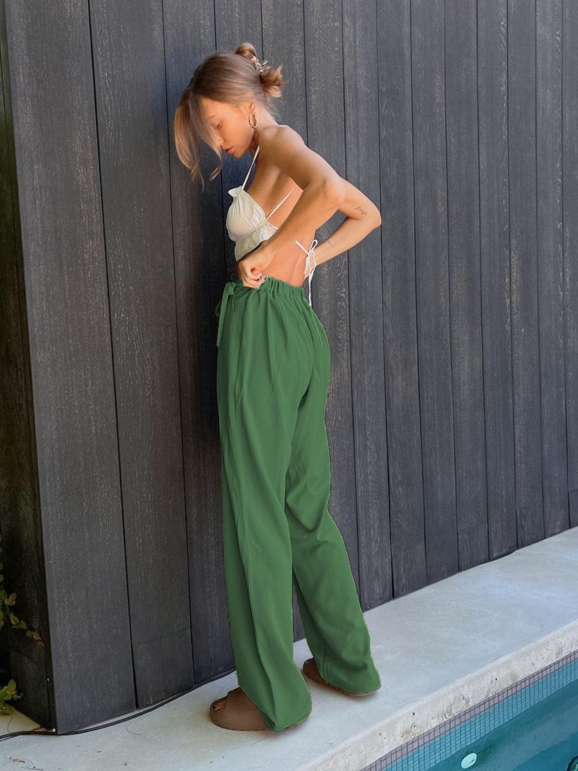 a woman leaning against a wall next to a pool