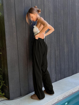 a woman leaning against a wall next to a swimming pool