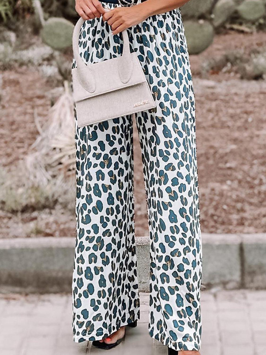 a woman in a leopard print jumpsuit holding a purse