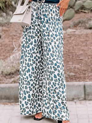 a woman wearing a leopard print pants and a black top