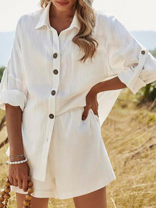 a woman standing in a field wearing a white shirt and shorts