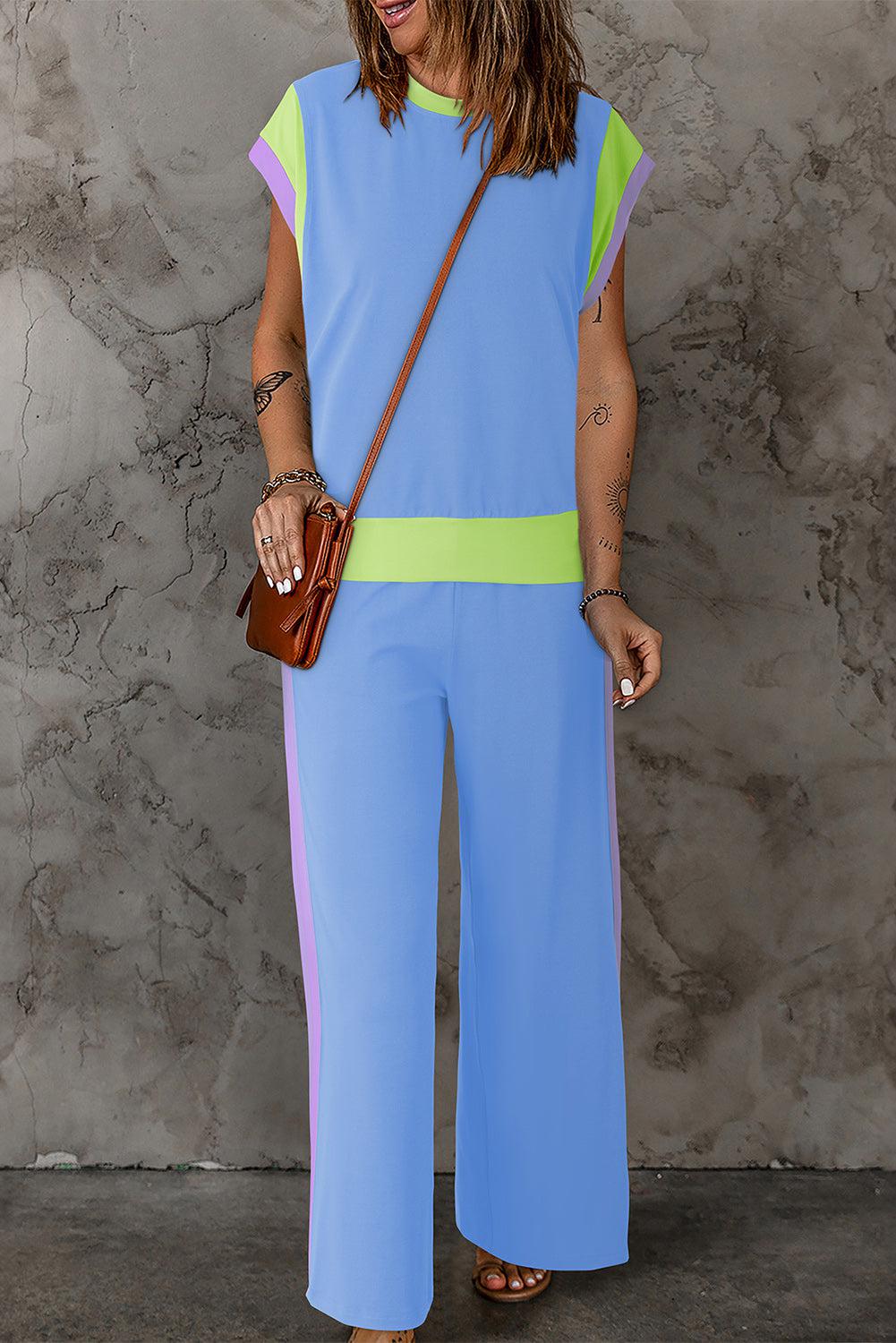 a woman in a blue and green jumpsuit holding a brown purse